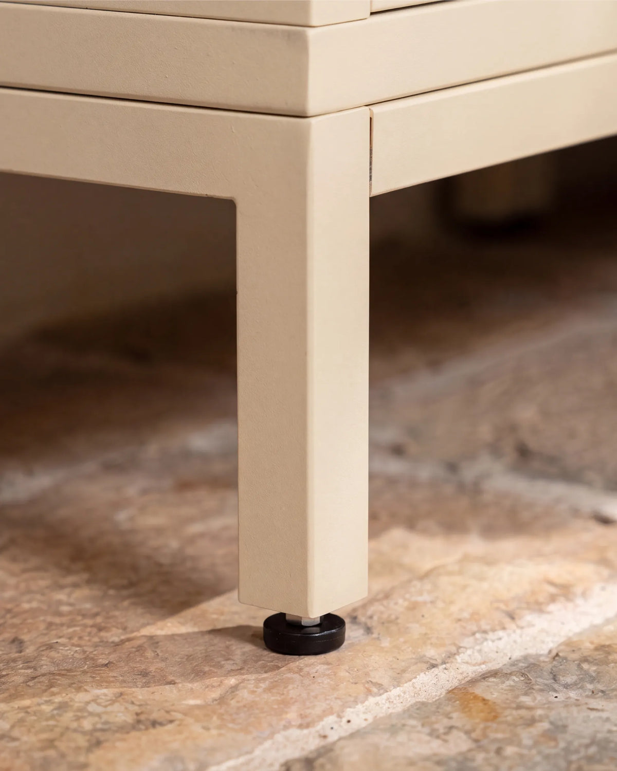 Beige cream metal leg of the PILOTIS structure with leveling screw, close-up on stone floor