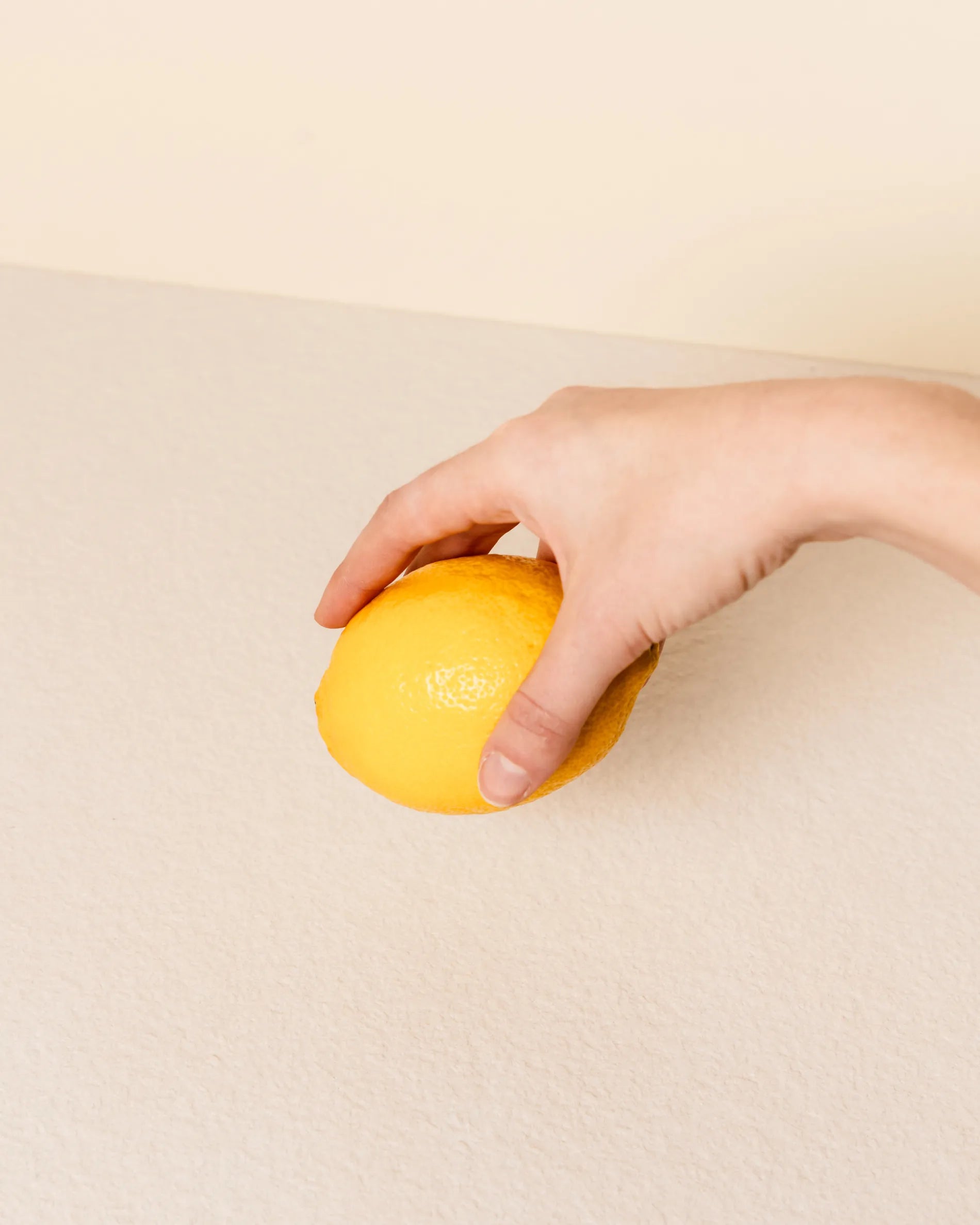 Hand holding a lemon above the beige cream tray of the Classic PILOTIS module, close-up