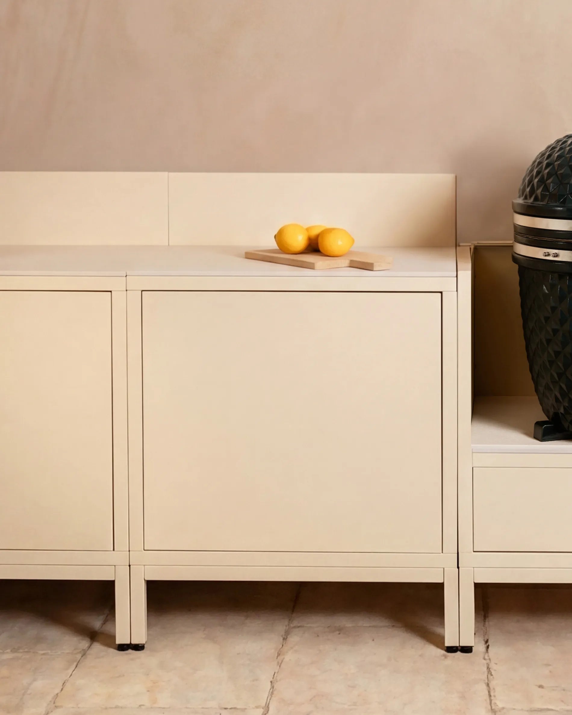 Beige cream Classic PILOTIS module units in the outdoor kitchen, featuring a kamado and lemons on a board