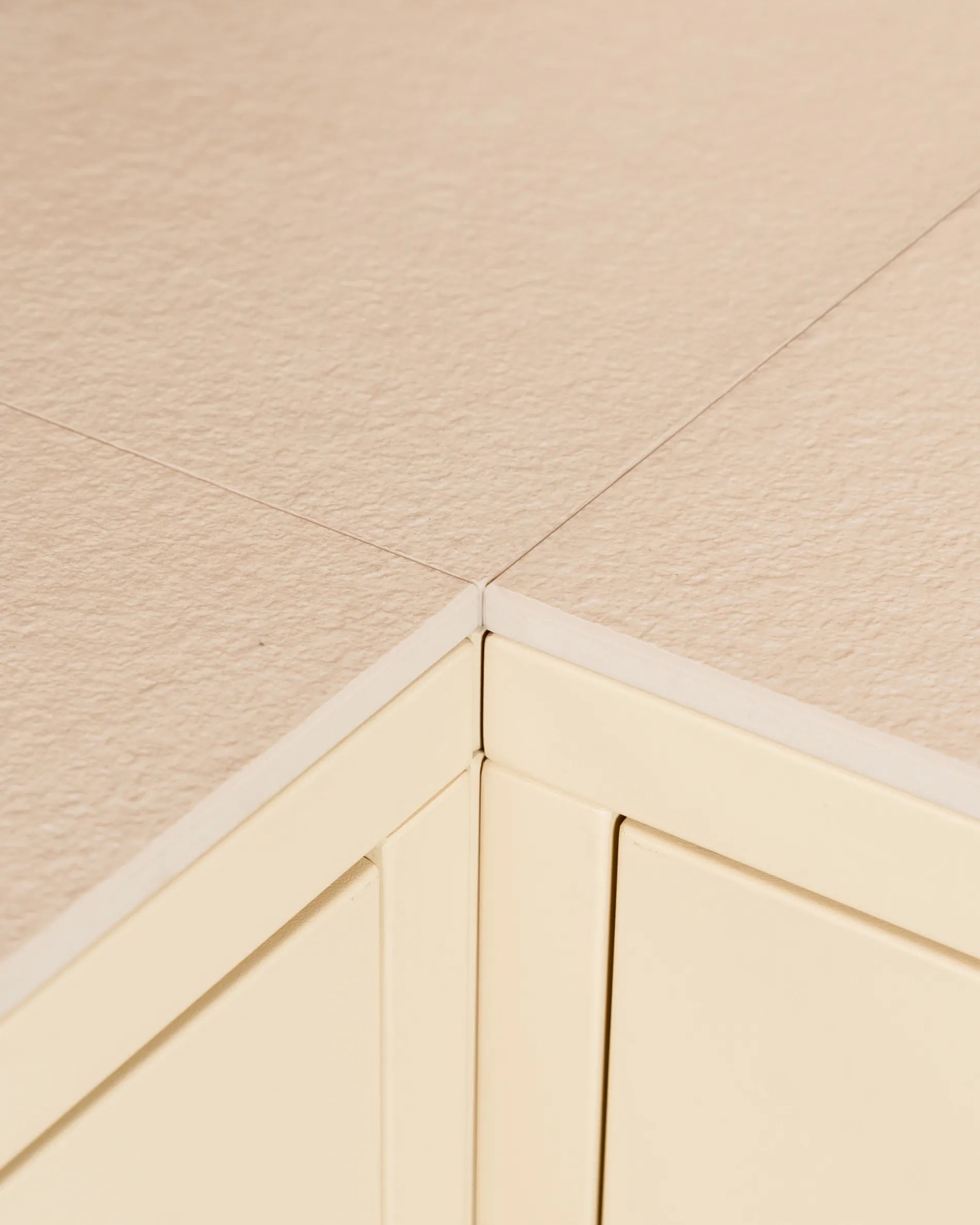 Close-up of the corner joint of the PILOTIS cream beige tabletop, highlighting the cutout of the frame