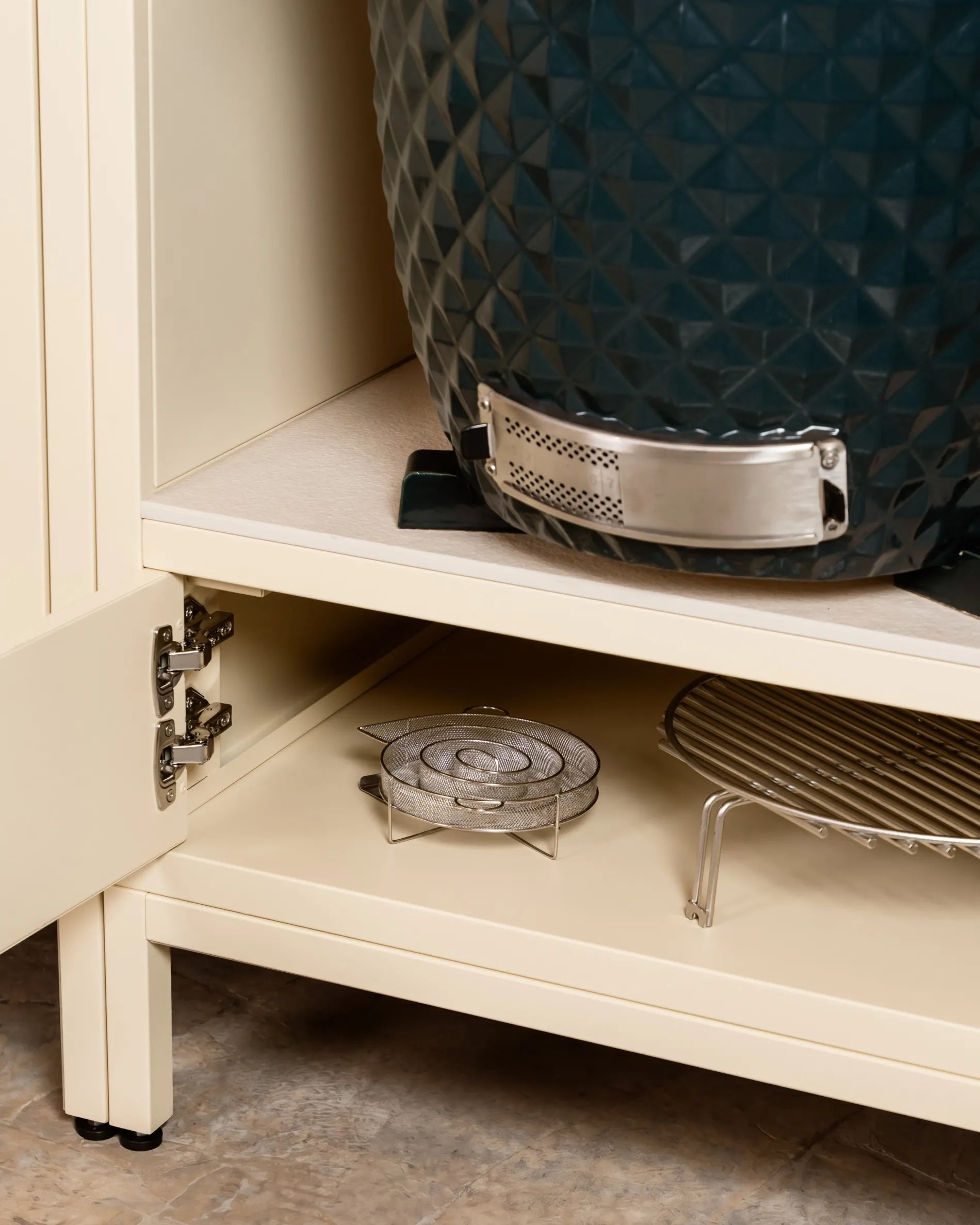 Navy blue Kokko kamado barbecue in the cream beige PILOTIS cabinet niche, close-up of the hinge and storage racks