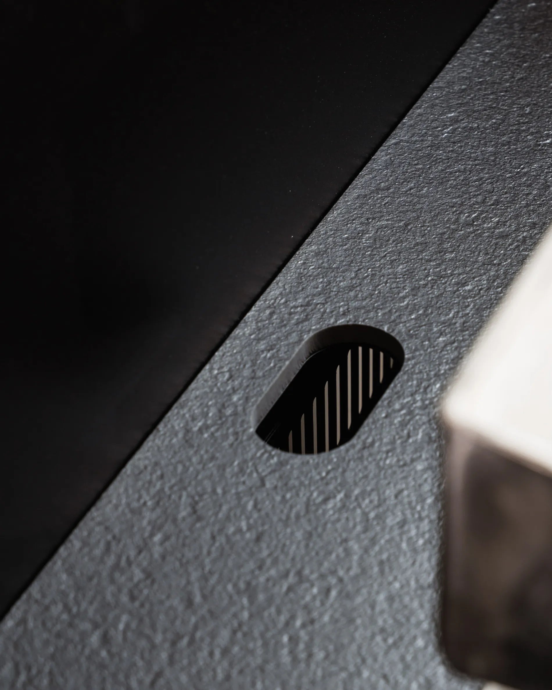 Oval cut-out of the black Plancha PILOTIS module tray, close-up of slate-effect texture