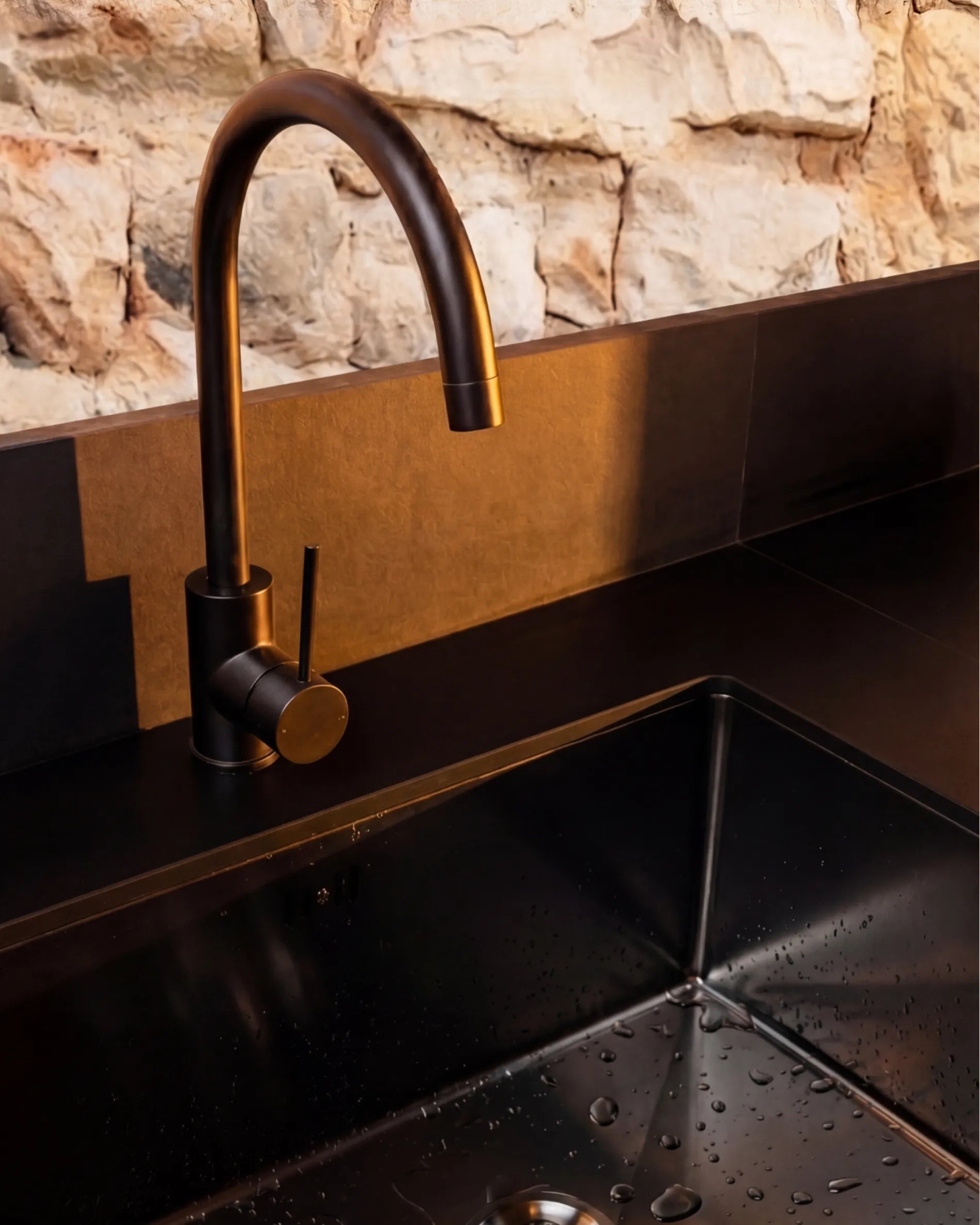 Close-up of the black basin and bronze-finish tap on the PILOTIS Sink module