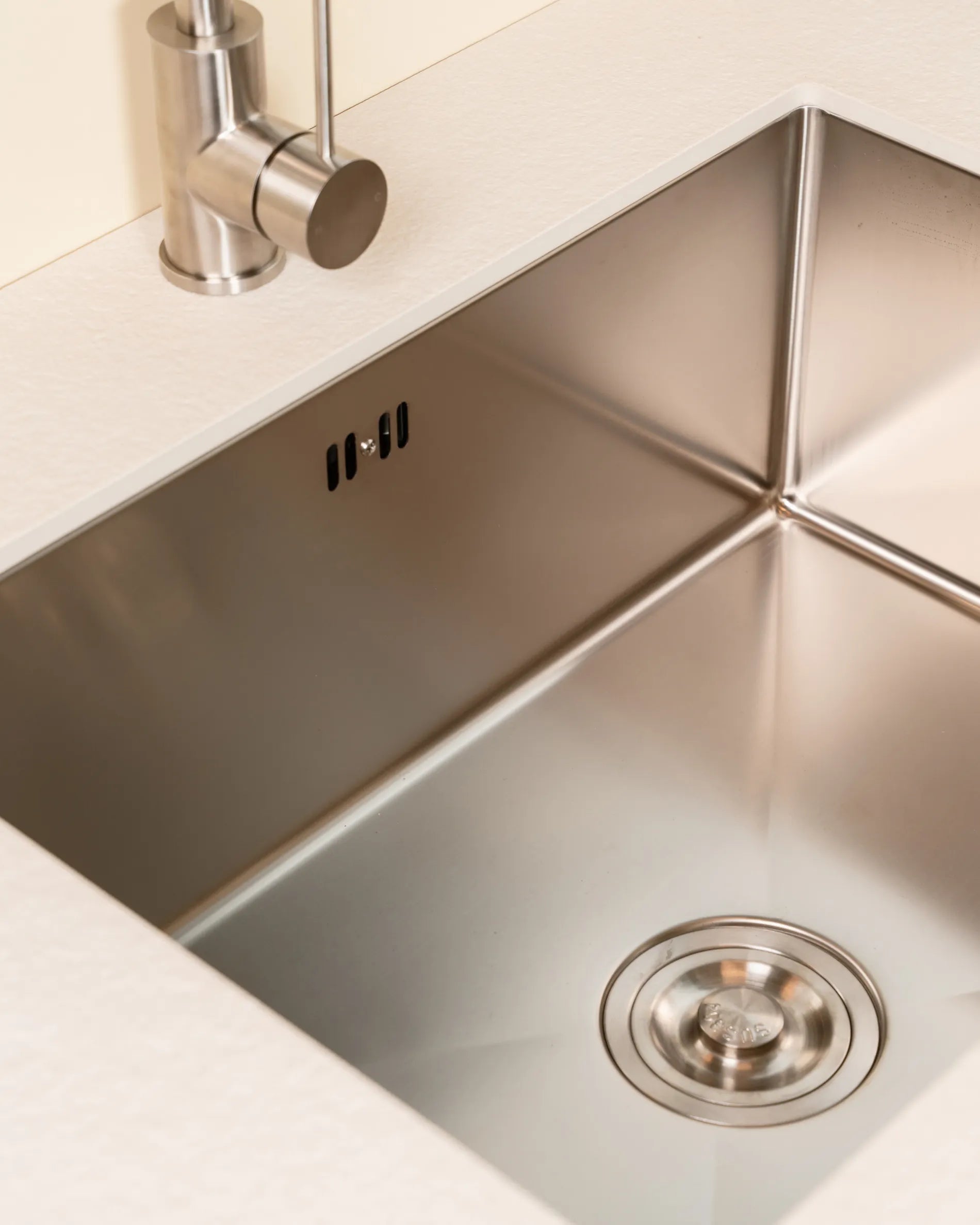 Close-up of the stainless steel sink of the PILOTIS Sink Module, embedded in a beige cream countertop