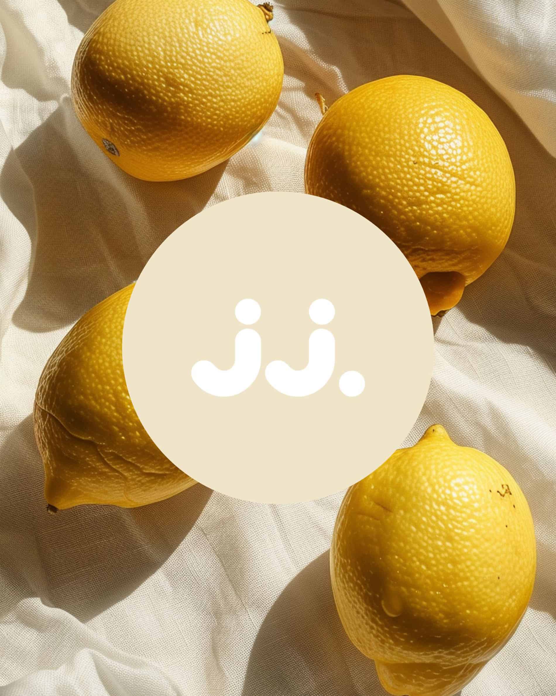 Yellow lemon on light fabric with jj. logo, evoking the scent of Lemongrass & Lemon.