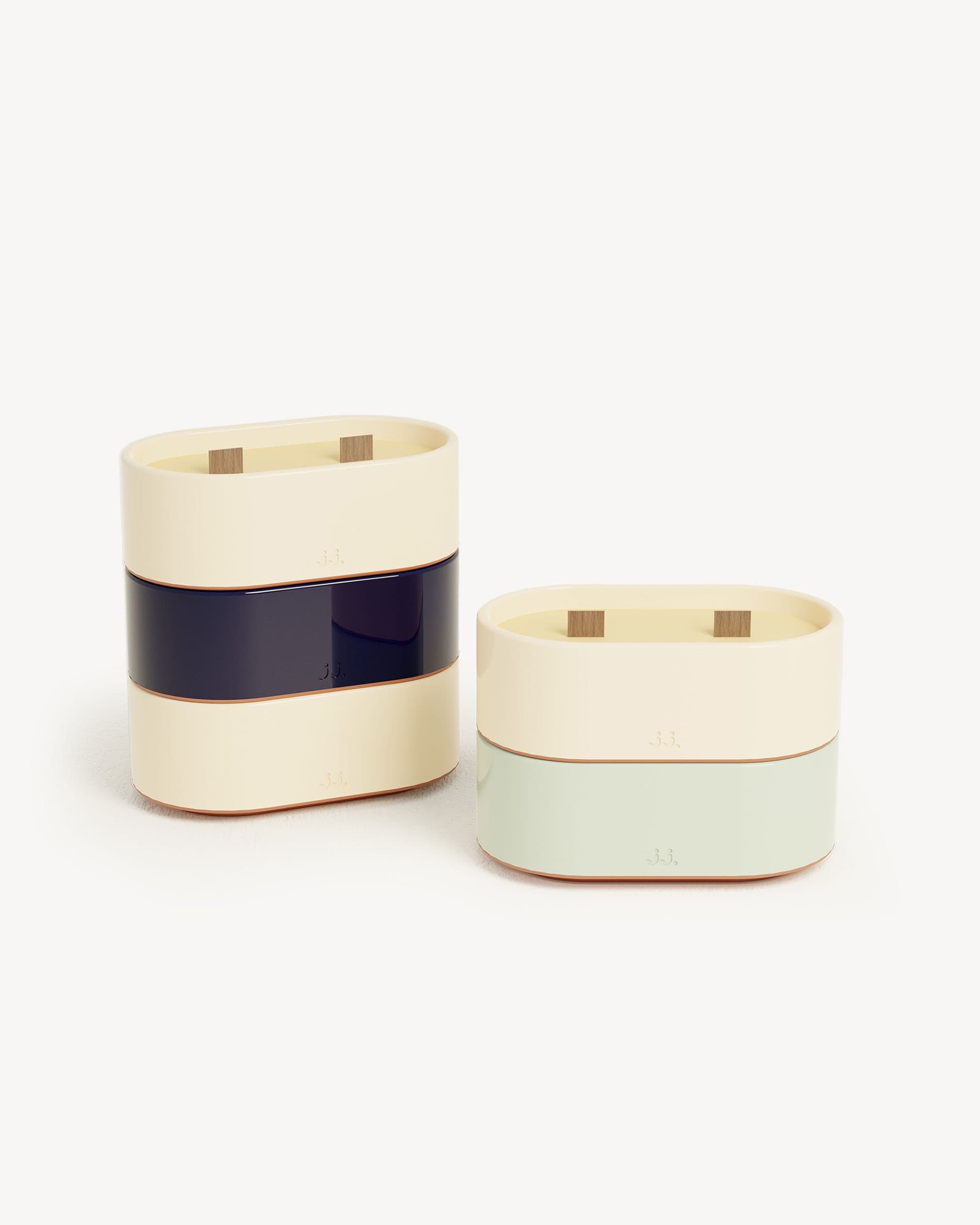 Totem S candle in two-tone ivory beige and navy blue ceramic, scented with citronella and notes of lemon and sea salt, shown next to a water green eucalyptus version.