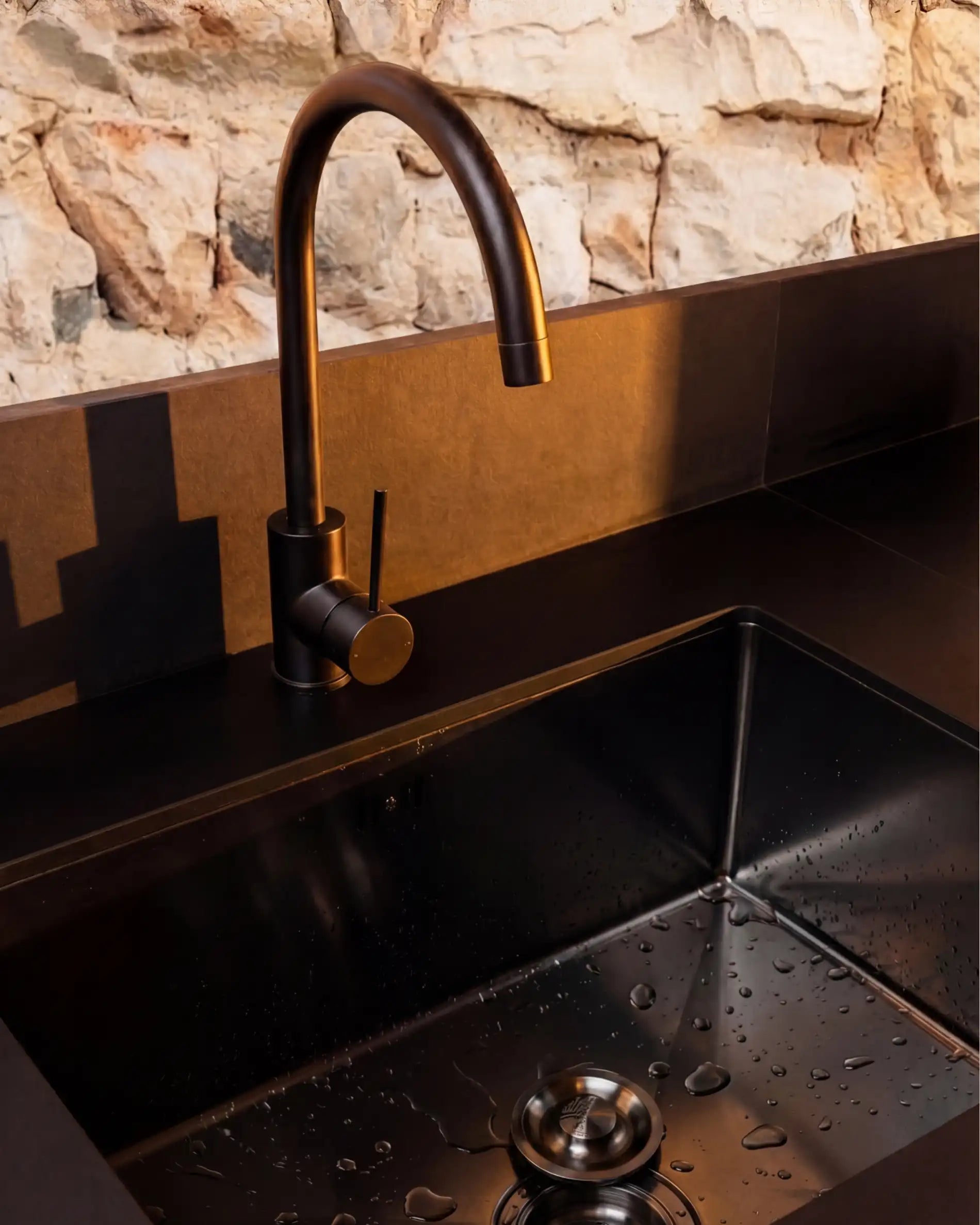 Stainless steel sink detail with black faucet on Kokko outdoor kitchen
