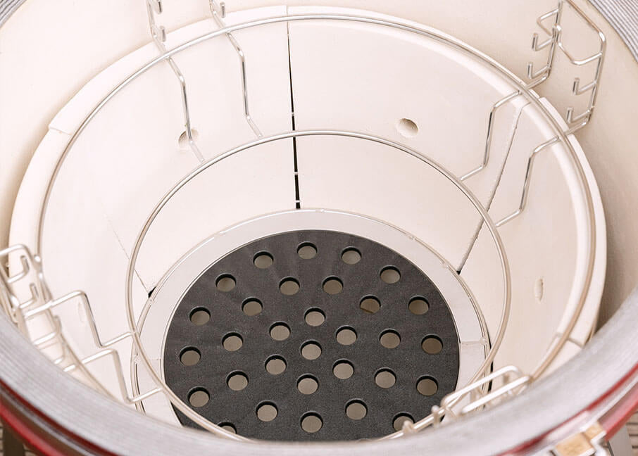 Vue intérieure de la cuve en céramique du kamado Kokko, montrant la structure divisée et le fond perforé pour la gestion des braises.