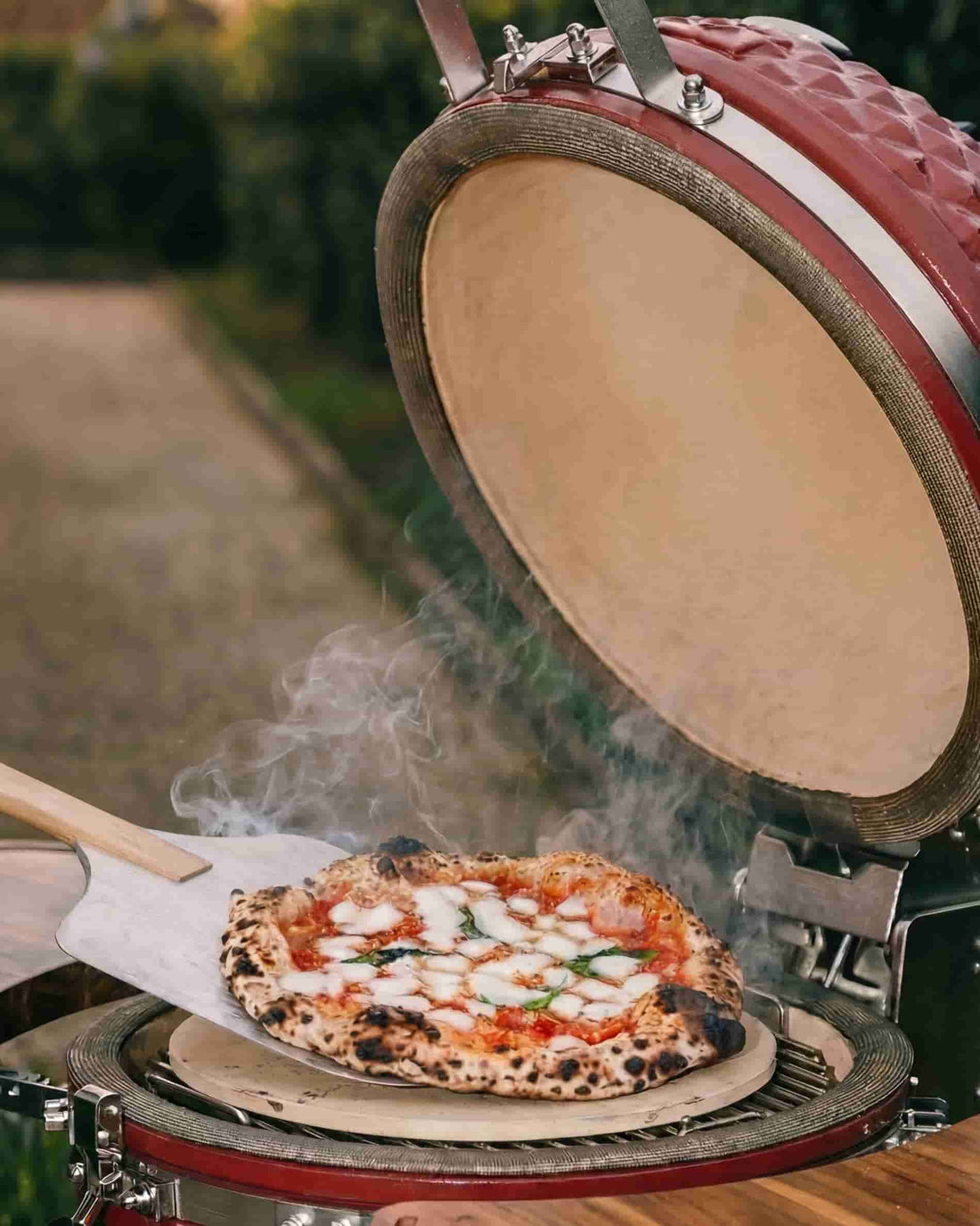 Pizza placed on a baking stone inside an open Kokko kamado, wood-fired charcoal cooking.