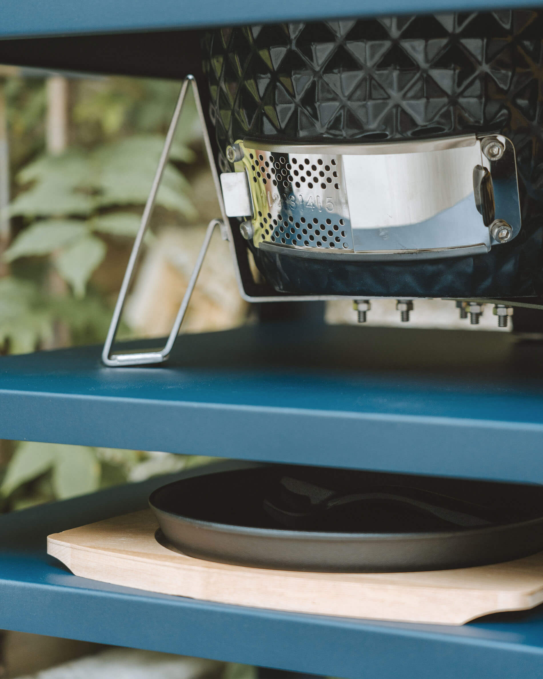 Close-up of the stainless steel lower vent on a Kokko kamado, built into a metal cart with an ash collection tray.