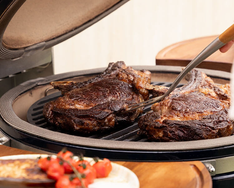 Direct cooking on the Kokko XL 22-inch kamado, showing food being seared on the stainless steel grill.