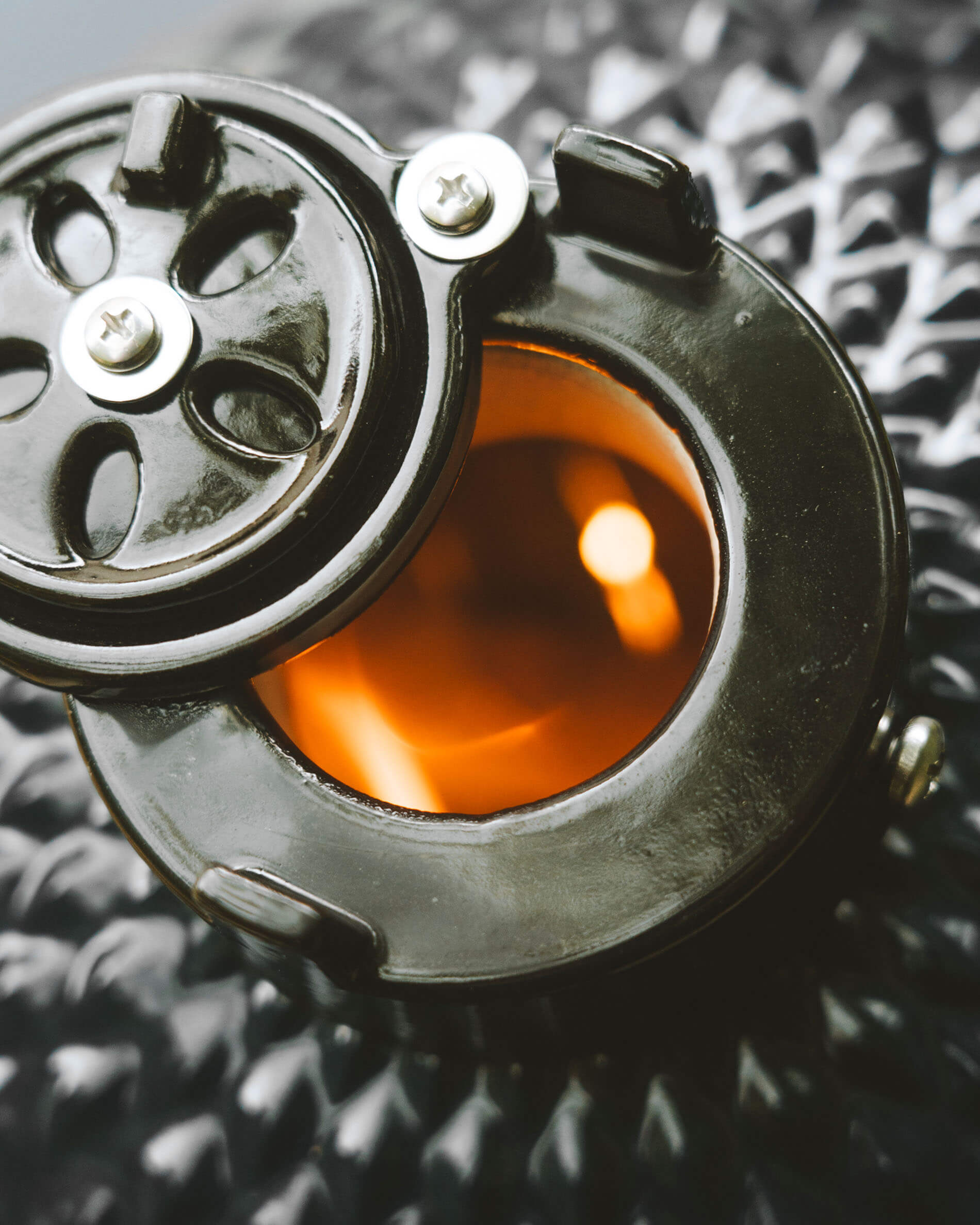 Vue rapprochée du système de ventilation supérieur d’un kamado Kokko, avec ouverture circulaire et foyer incandescent visible.