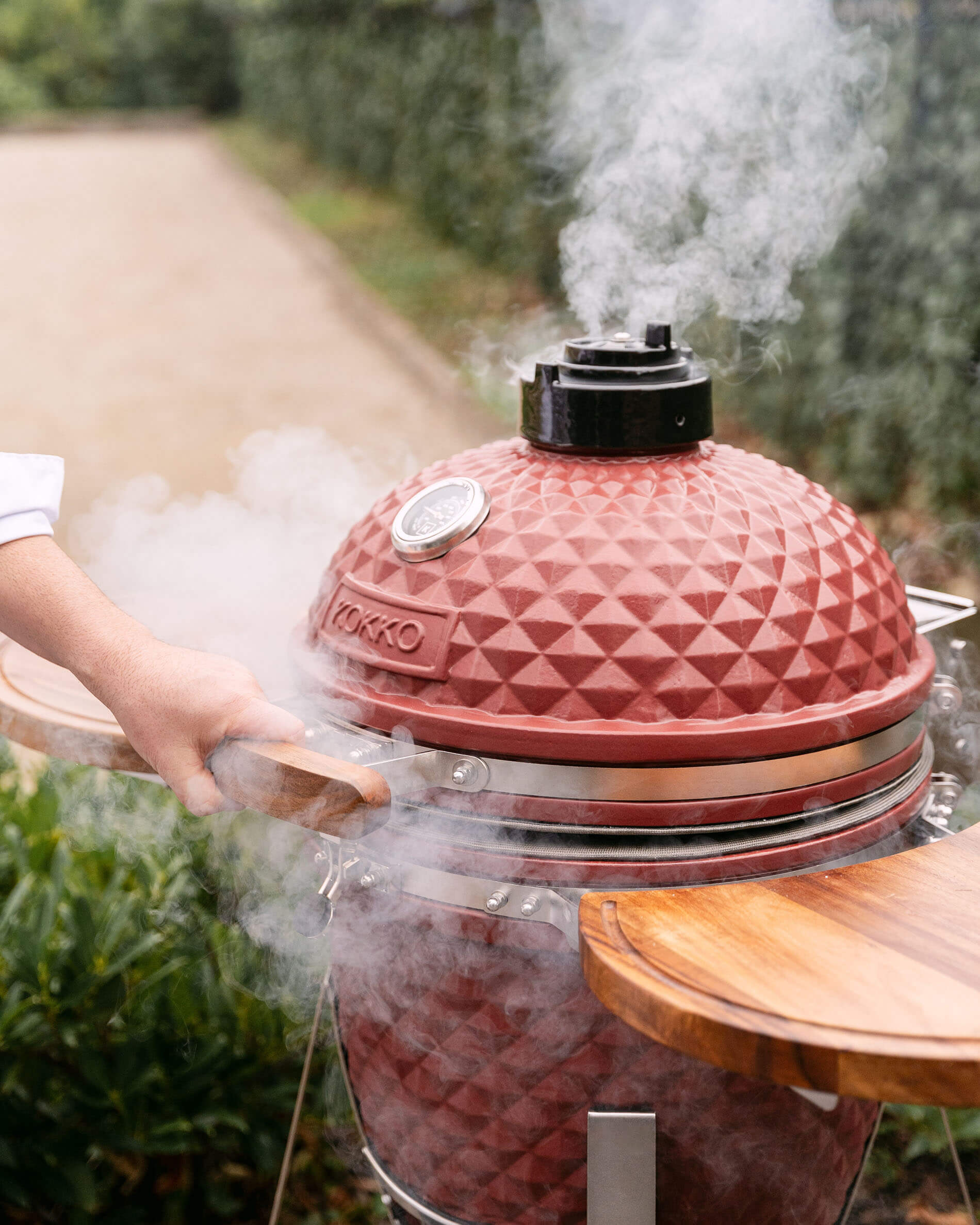 Kokko L 18-inch ceramic kamado in oxide red with cooking smoke.