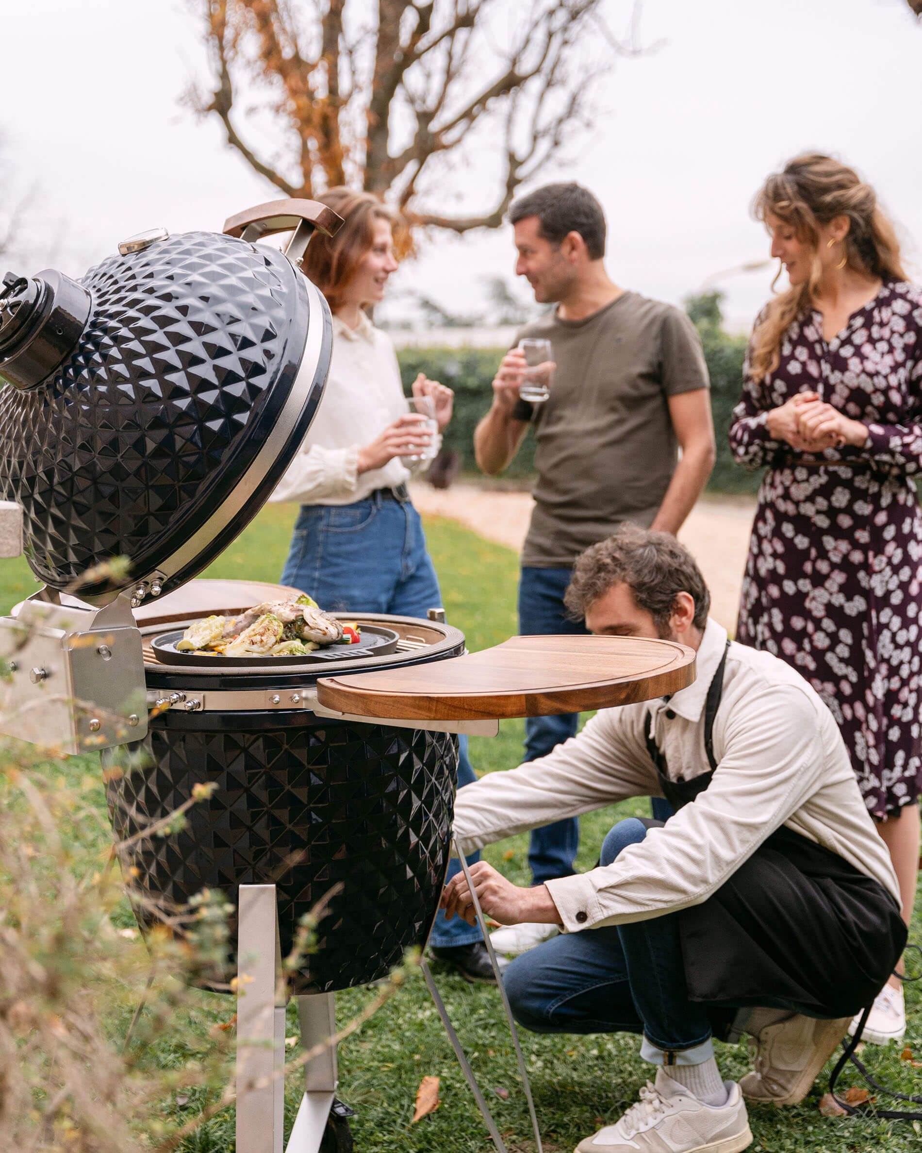 Navy blue Kokko 22-inch ceramic kamado in use during a friendly outdoor gathering.