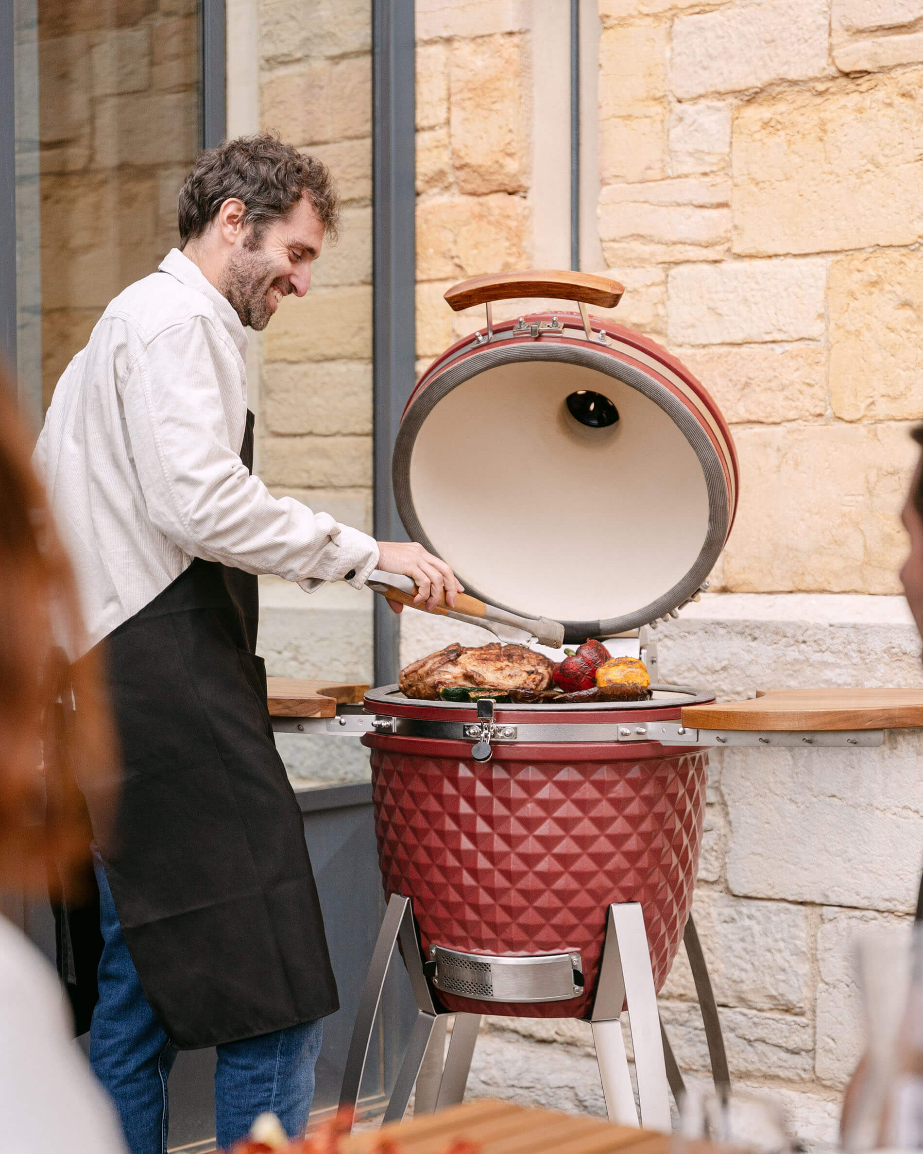 Red oxide ceramic Kokko kamado in use for outdoor cooking.