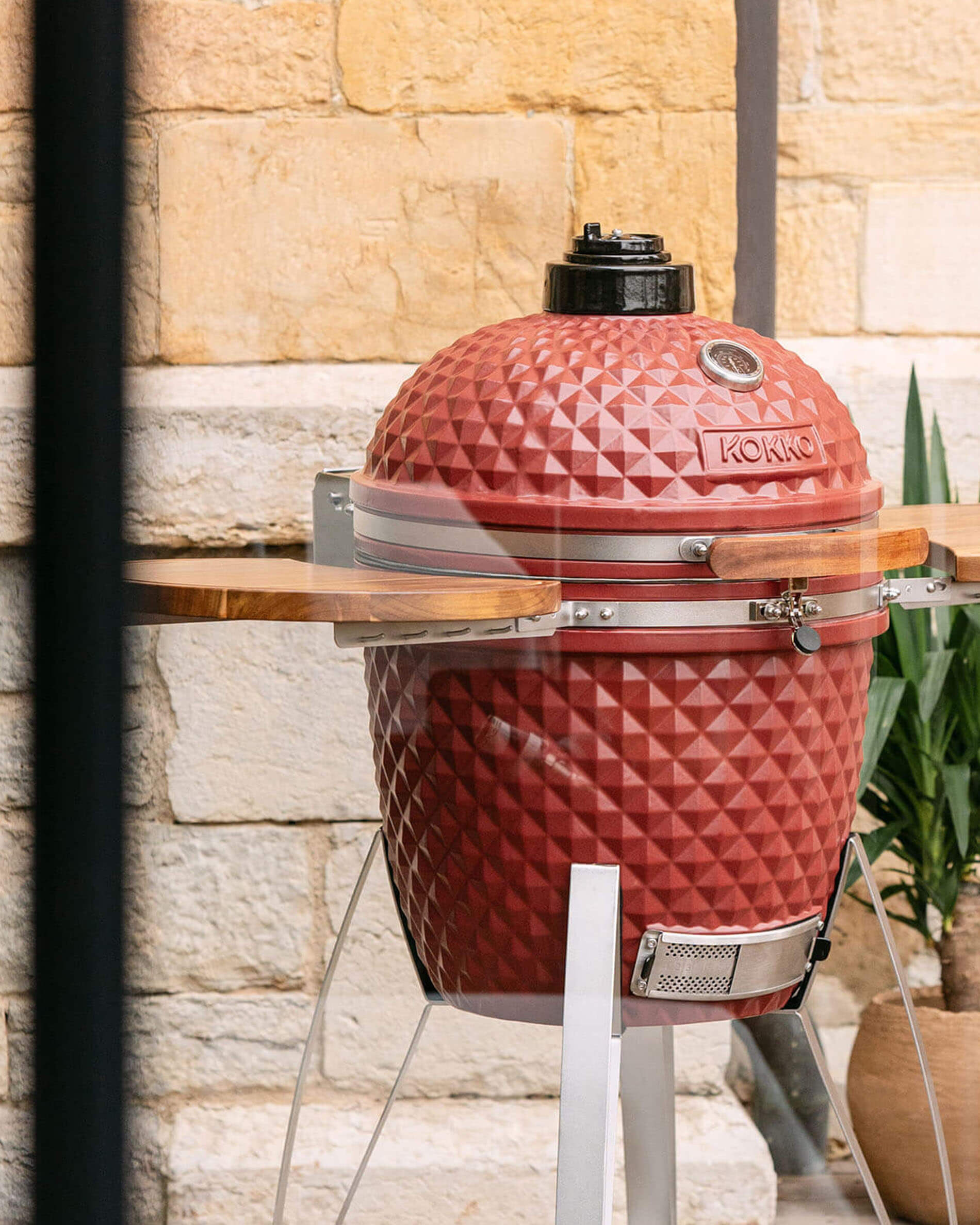 Kokko 22-inch red oxide kamado barbecue, shown alone outdoors.