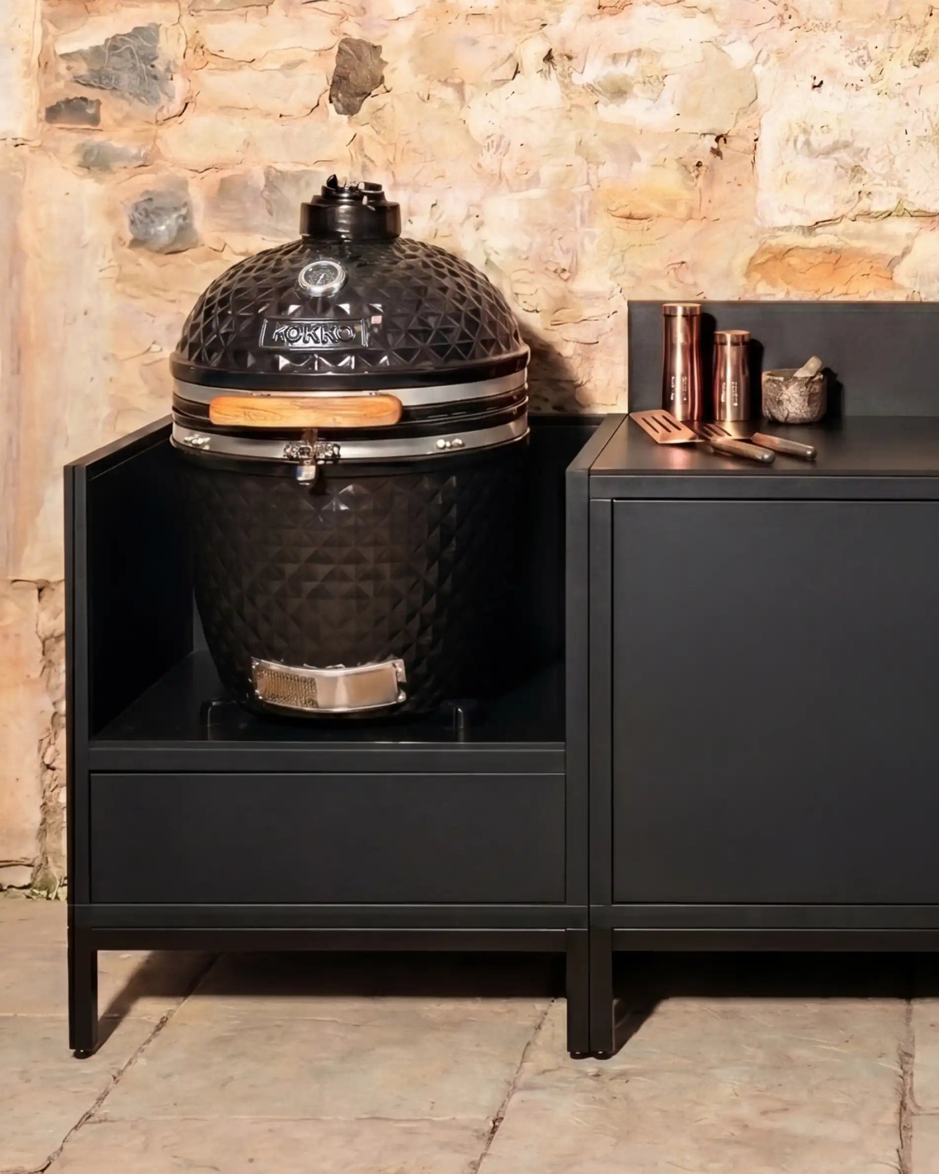 Black Kokko kamado built into outdoor kitchen with storage