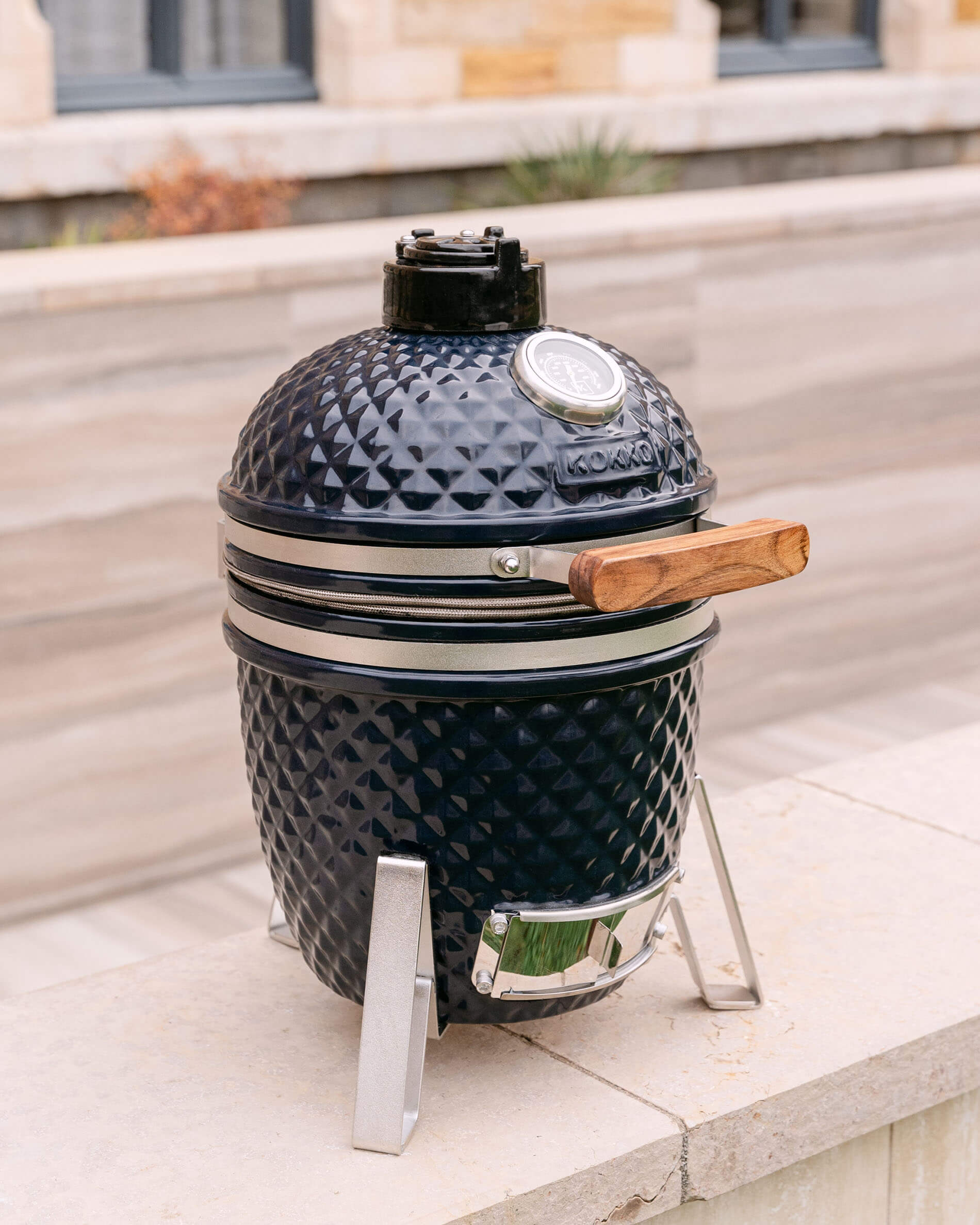 Kamado Little Kokko 13 bleu marine présenté sur son support en extérieur.