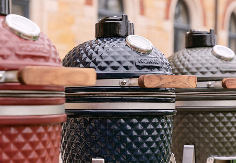Lineup of Kokko kamados in various models and colors, displayed side by side outdoors.