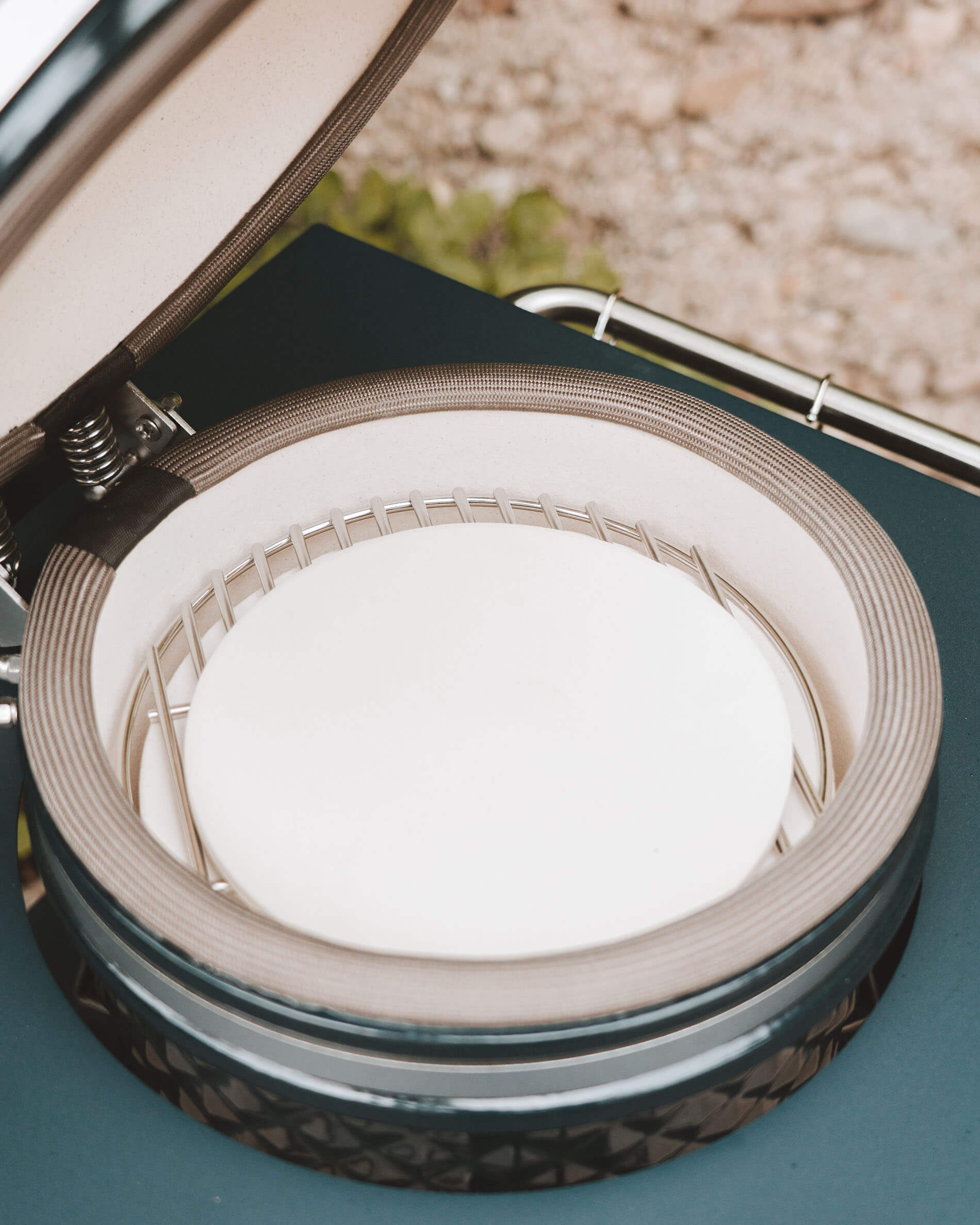 Intérieur du kamado Kokko avec pierre à pizza installée sur le support de cuisson, vue détaillée de la céramique et du joint d’étanchéité.