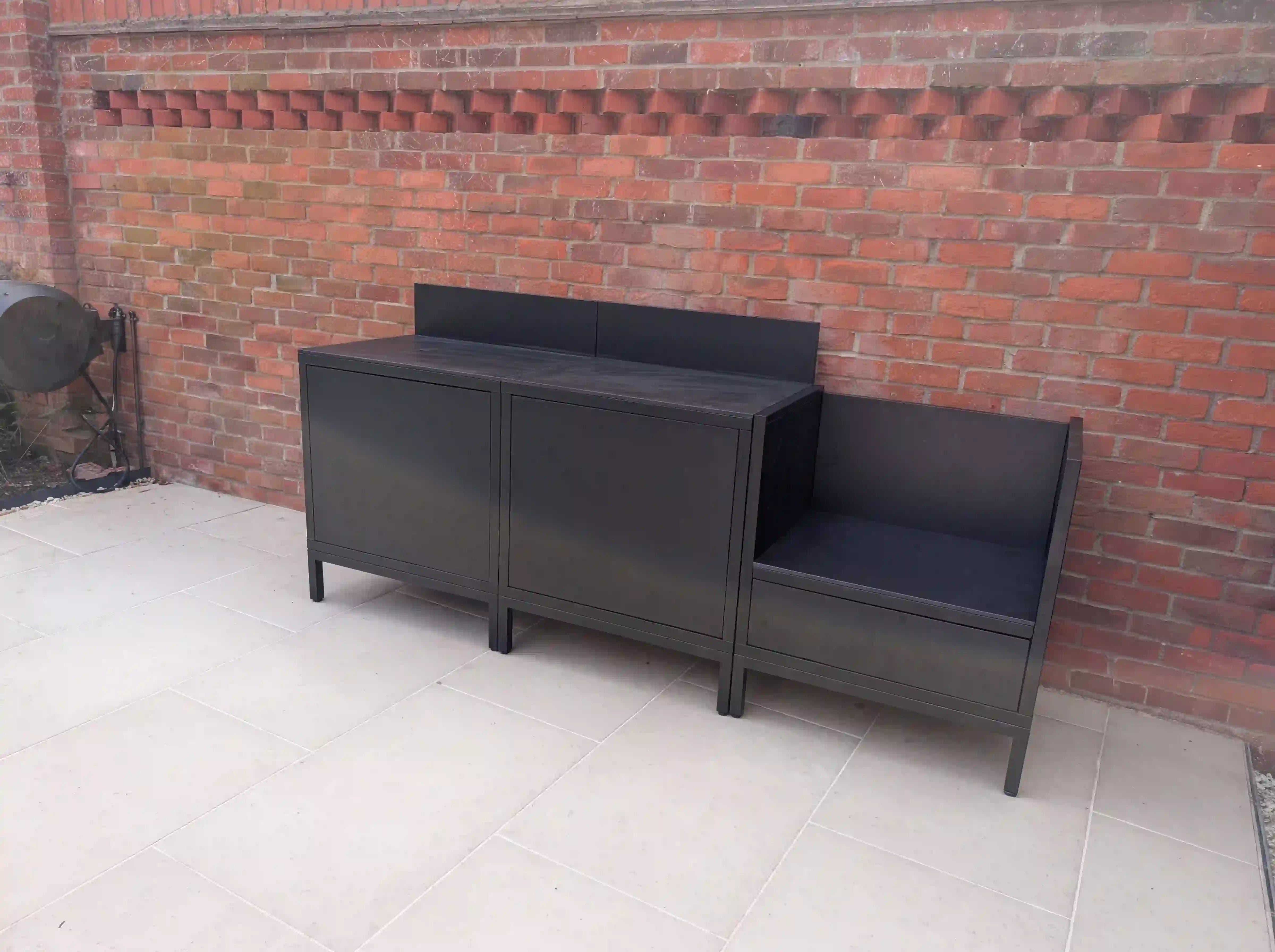 Outdoor PILOTIS kitchen in black installed by a customer, with an empty Kamado module, set against a brick wall