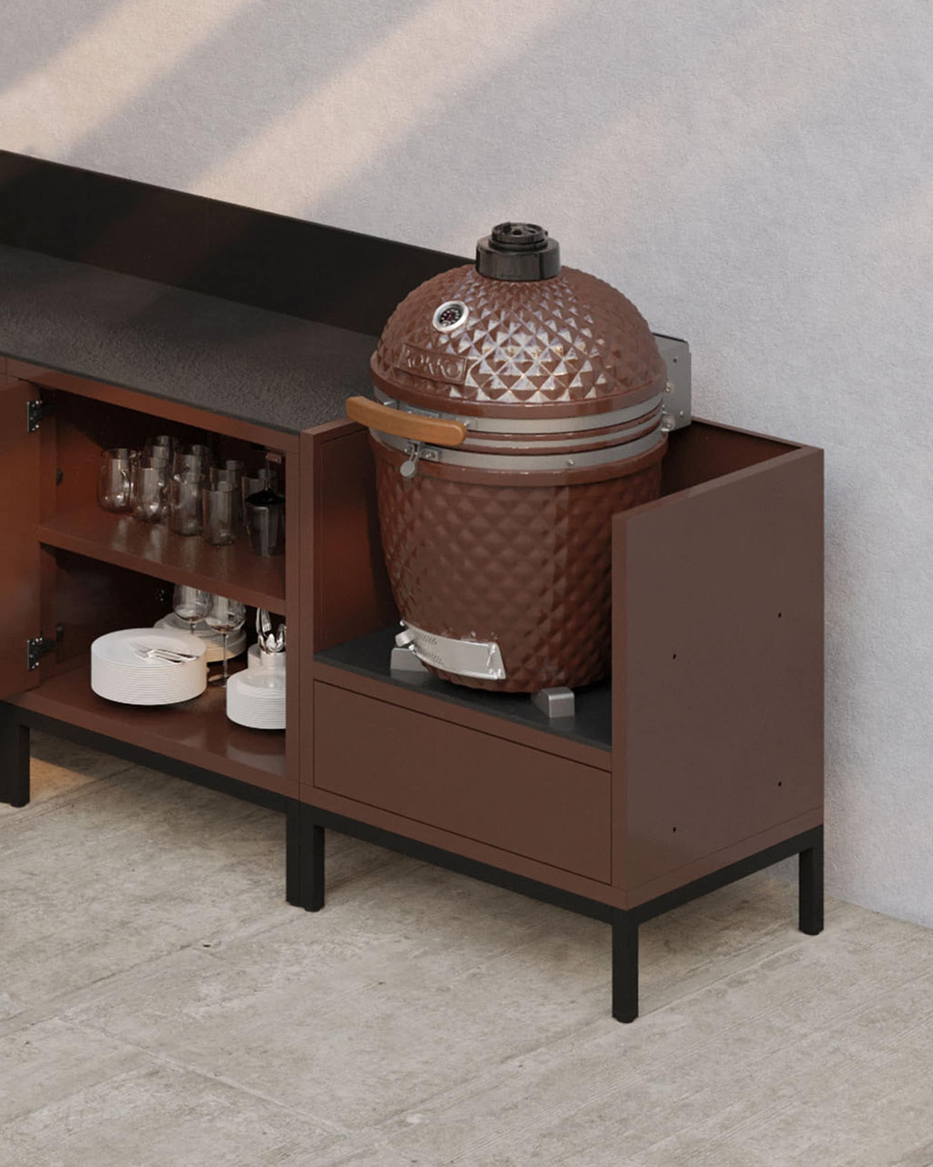 Cuisine pilotis modulable coloris rouille avec plan de travail sombre, rangements ouverts et module conçu pour accueillir un kamado.