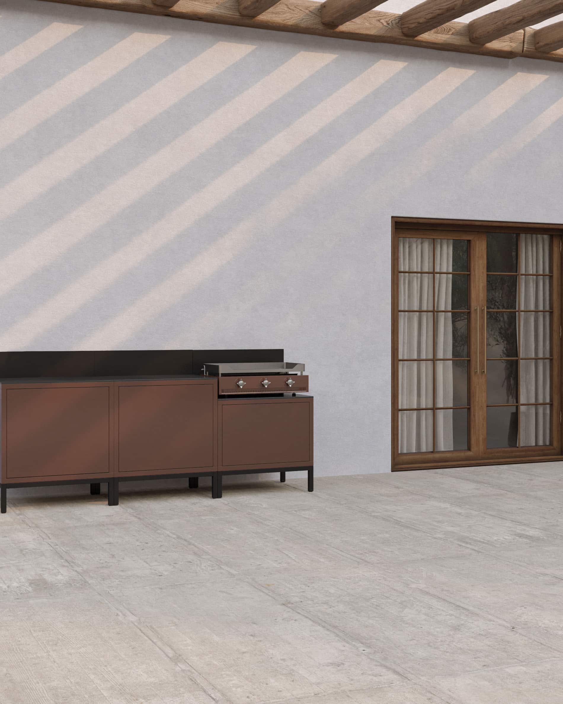 Cuisine extérieure pilotis avec plancha intégrée, meubles coloris brun rouille, rangements fermés et plan de travail sombre, installée sur une terrasse couverte.