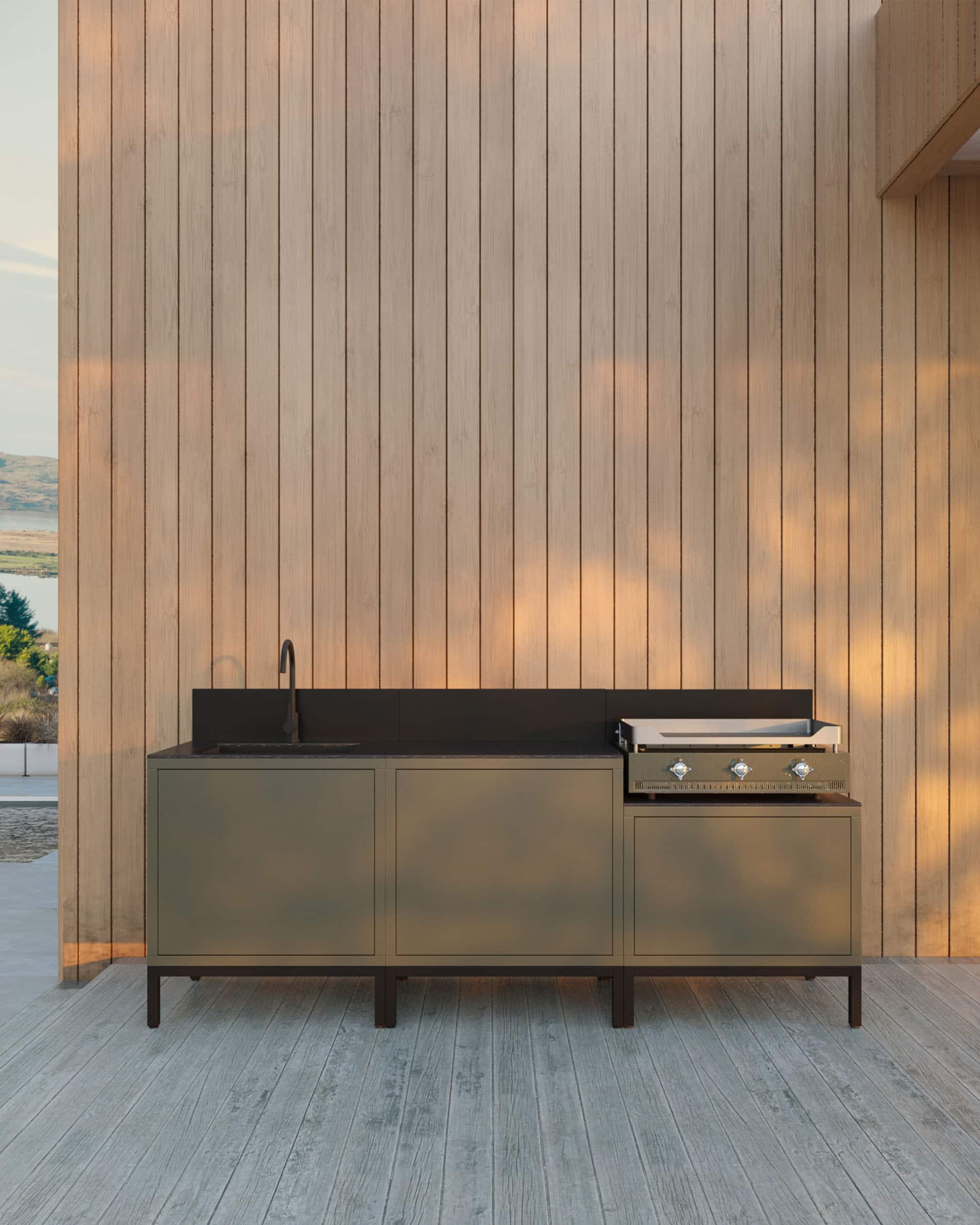 Cuisine extérieure Kokko avec plancha intégrée, meuble de rangement vert, évier et plan de travail noir, installée sur une terrasse en bois.